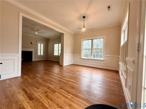 a view of an empty room with wooden floor fireplace and a window