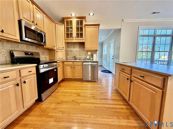 a kitchen with stainless steel appliances granite countertop a stove a sink dishwasher and a refrigerator with wooden floor