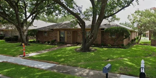 a backyard of a house with plants and large tree