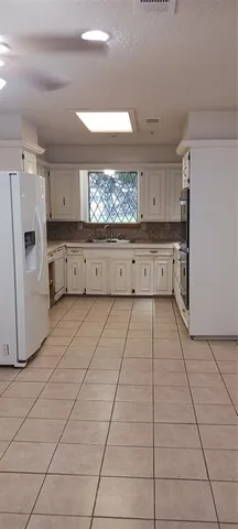 a view of an empty room with window and chandelier fan