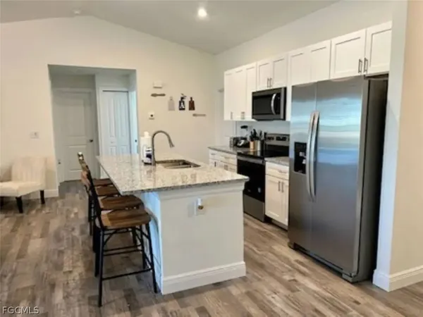 a kitchen with stainless steel appliances granite countertop a table chairs and a refrigerator