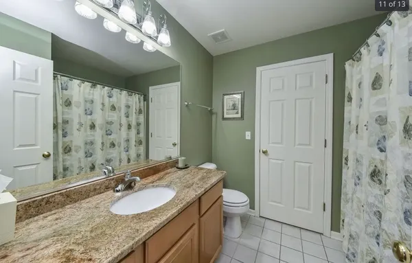 a bathroom with a granite countertop sink a toilet and shower