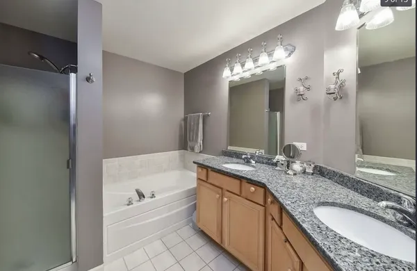 a spacious bathroom with a granite countertop tub double vanity and a mirror