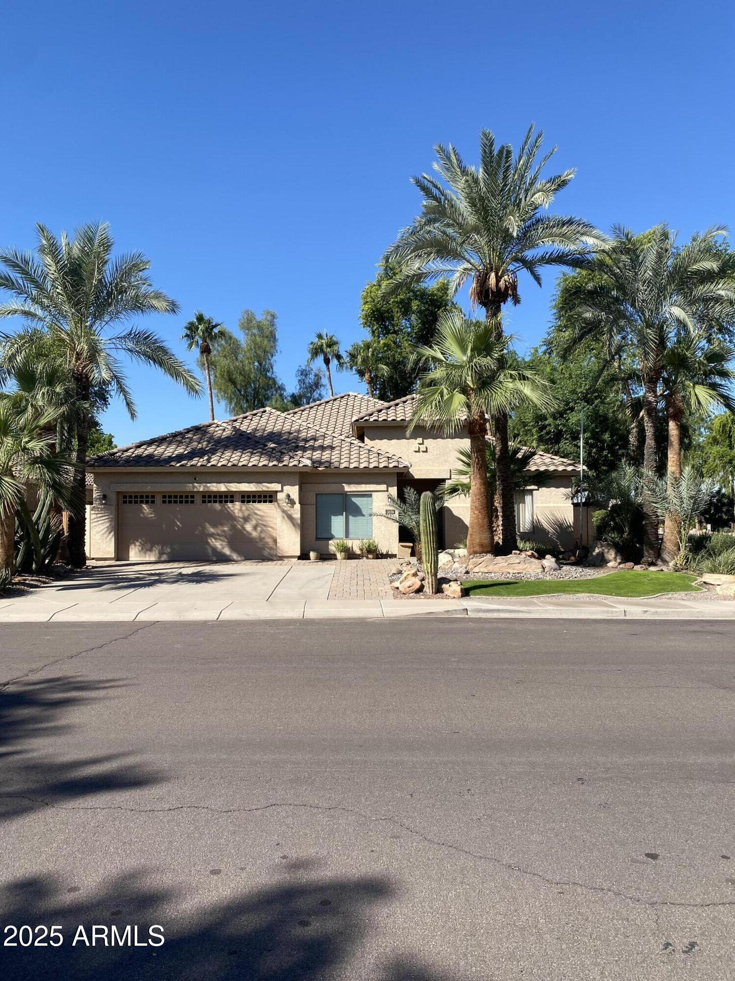 a front view of a house with a yard and palm trees