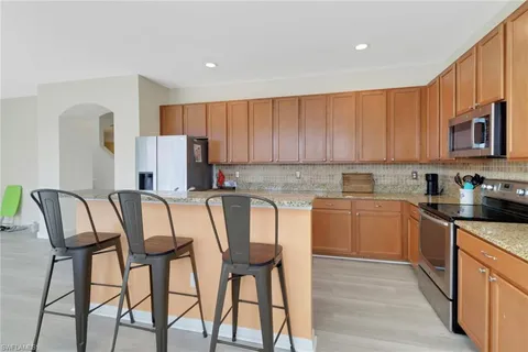 a kitchen with stainless steel appliances granite countertop a table chairs sink and cabinets
