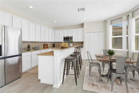 a kitchen with stainless steel appliances granite countertop a stove a refrigerator a white table and chairs with wooden floor