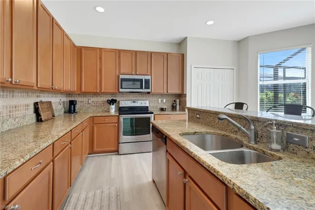 a kitchen with kitchen island granite countertop a sink a counter top space cabinets and stainless steel appliances