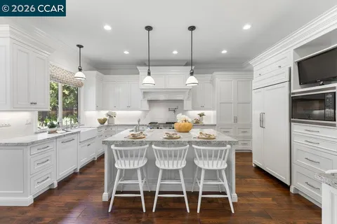 a kitchen with stainless steel appliances kitchen island granite countertop a dining table chairs and sink