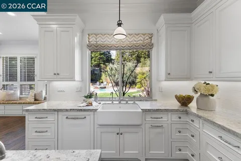 a kitchen with white cabinets and a window