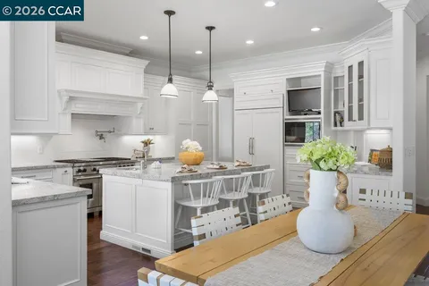 a kitchen with stainless steel appliances kitchen island granite countertop a stove a sink and a white cabinets