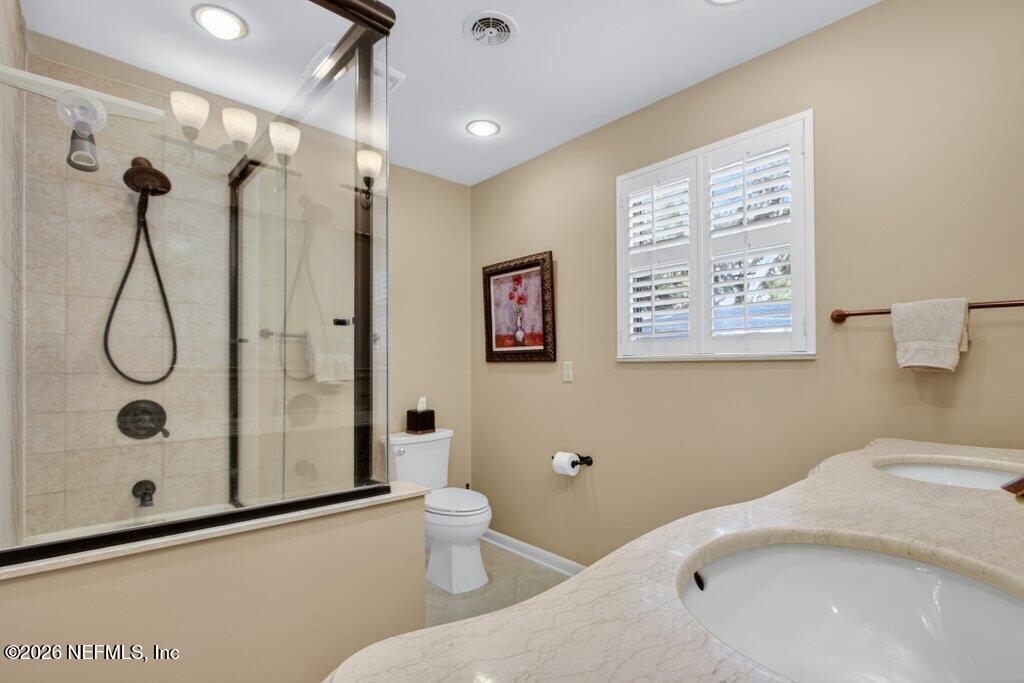 8349 Kim Road Jacksonville, FL 32217 - Photo 37 of 73 a bathroom with a granite countertop sink a toilet and a shower