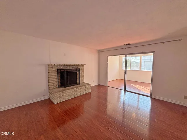an empty room with wooden floor and fireplace