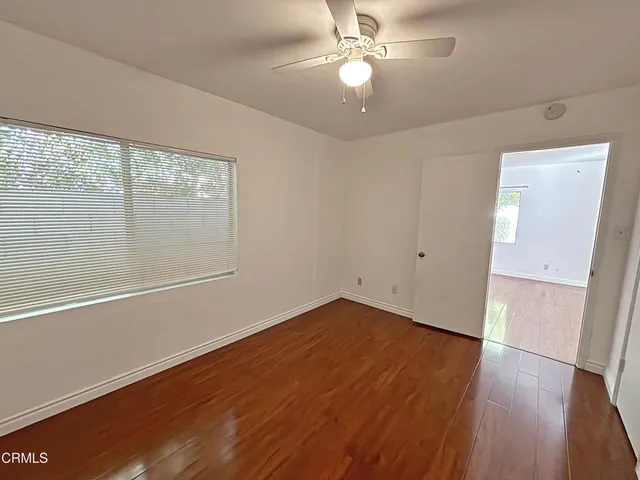 an empty room with wooden floor fan and windows