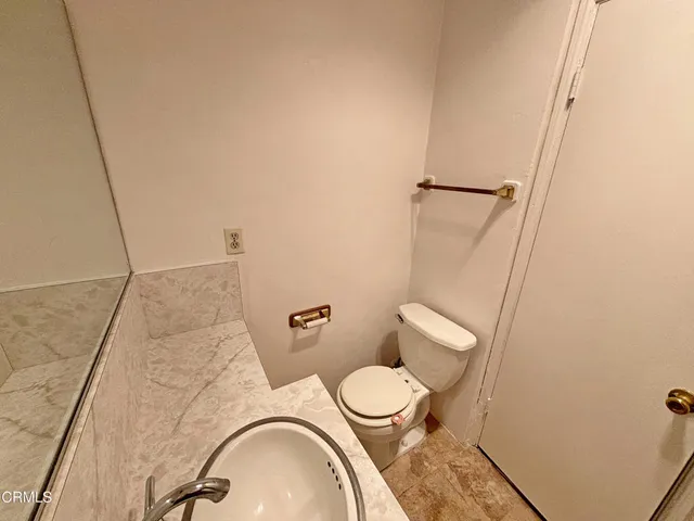 a white toilet sitting next to a bathroom sink and vanity