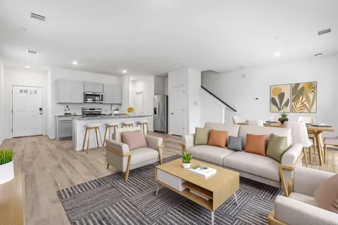 a kitchen with stainless steel appliances granite countertop a refrigerator a sink dishwasher a dining table and chairs with wooden floor