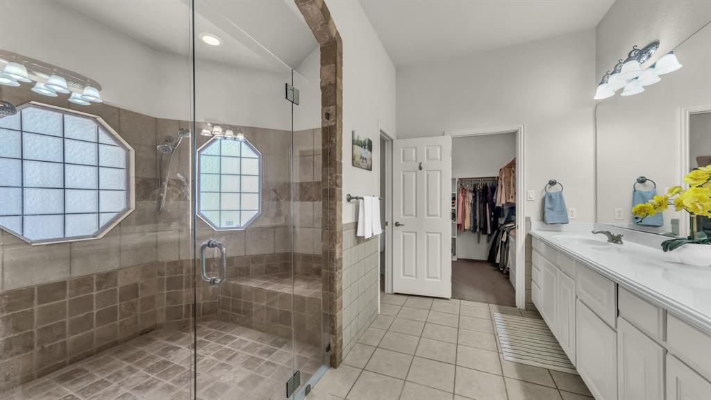 203 Mockingbird Lane Aledo, TX 76008 - Photo 25 of 37 Spacious bathroom featuring a glass-enclosed shower with integrated bench seating, dual octagonal windows, and a tiled surround