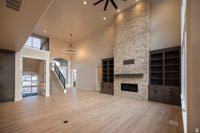 904 South 1900 West Layton, UT 84041 - Photo 5 of 19 Unfurnished living room featuring a high ceiling, a stone fireplace, light wood-style tile floors, a ceiling fan, and suspended lighting