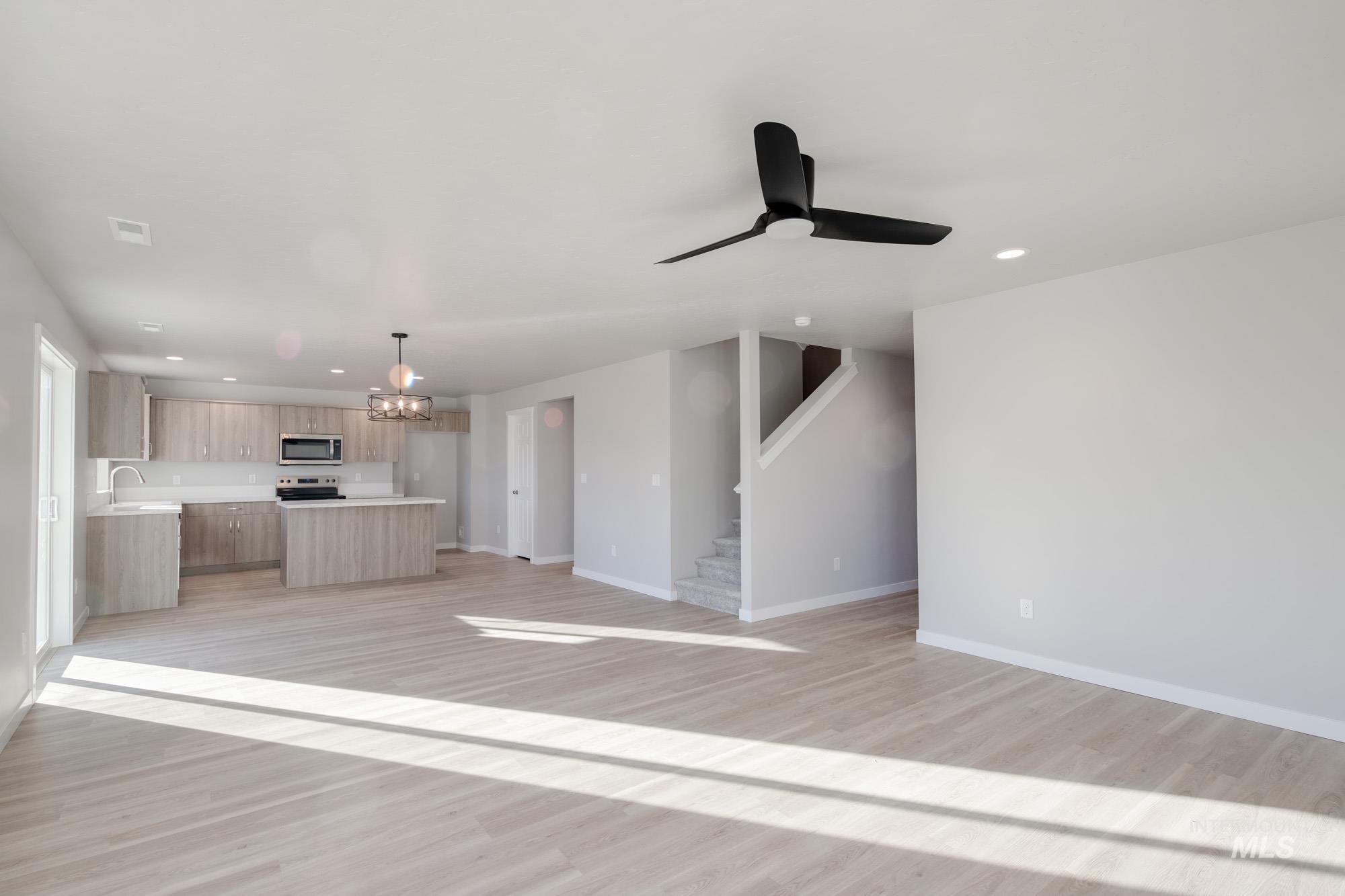 3210 South Maple Rnch Way Nampa, ID 83686 - Photo 6 of 22 Unfurnished living room featuring a chandelier, ceiling fan, recessed lighting, light wood-style floors, and stairway