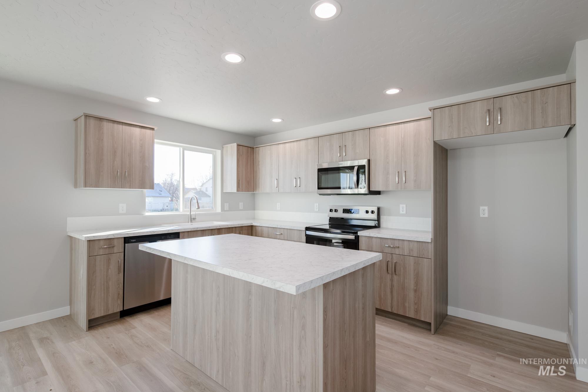 3210 South Maple Rnch Way Nampa, ID 83686 - Photo 8 of 22 Kitchen with a center island, stainless steel appliances, light countertops, light brown cabinetry, and recessed lighting