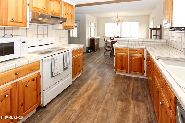 a kitchen with stainless steel appliances a white stove top oven a sink and white cabinets with wooden floor