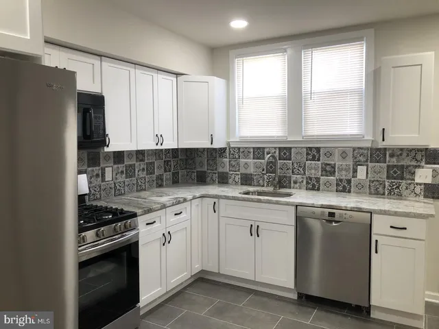 a kitchen with cabinets appliances a sink and a window