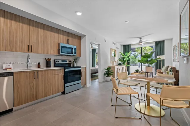 a kitchen with stainless steel appliances kitchen island granite countertop a stove a sink a microwave a dining table and chairs