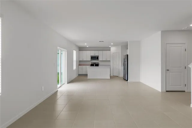 a view of a kitchen with refrigerator and white cabinets