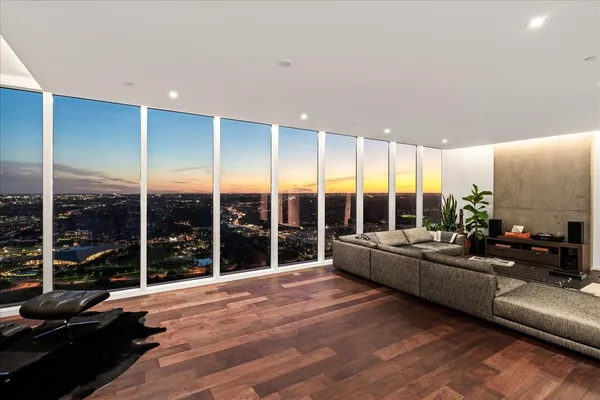 a living room with furniture large windows a rug and a floor to ceiling window