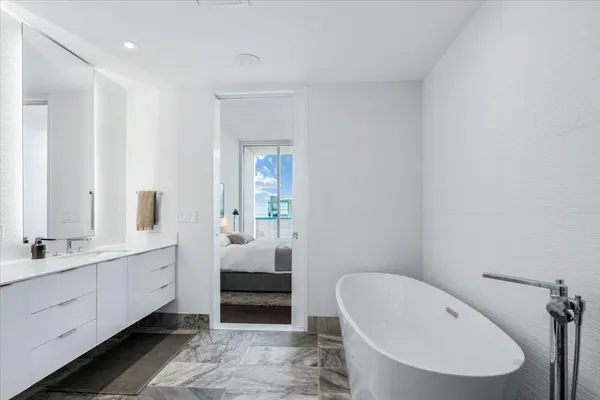 a en suite bathroom with a granite countertop sink and a bathtub