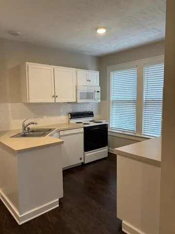 a kitchen with stainless steel appliances granite countertop a sink a stove and white cabinets with wooden floor