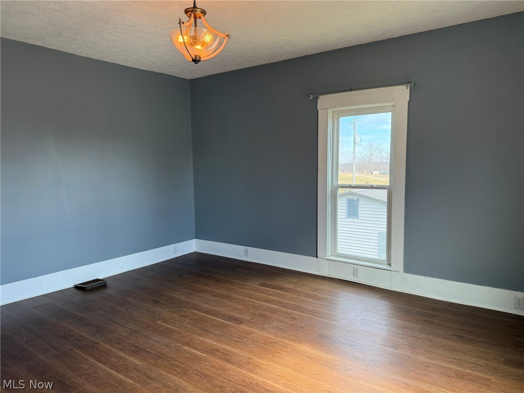 23033 Cadiz Road Freeport, OH 43973 - Photo 19 of 31 Unfurnished room featuring dark wood finished floors and a textured ceiling