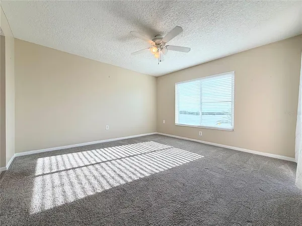 an empty room with windows and fan
