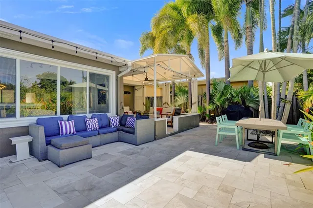 a view of a patio with couches and table under an umbrella with a palm tree