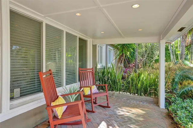 a porch with a table and chairs and potted plants