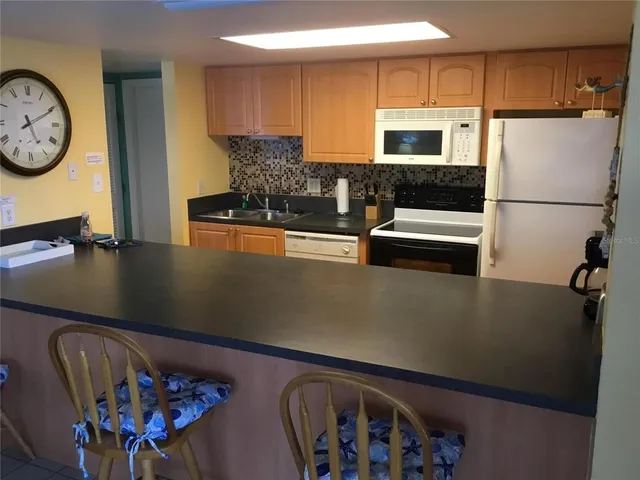 a kitchen with stainless steel appliances granite countertop a refrigerator a stove and a sink