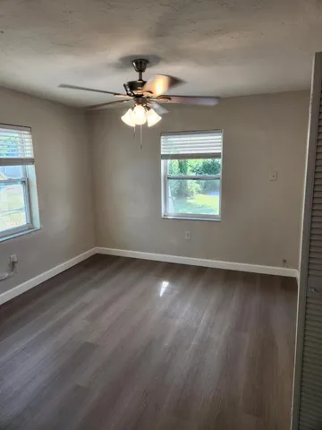 a view of an empty room with a window and wooden floor