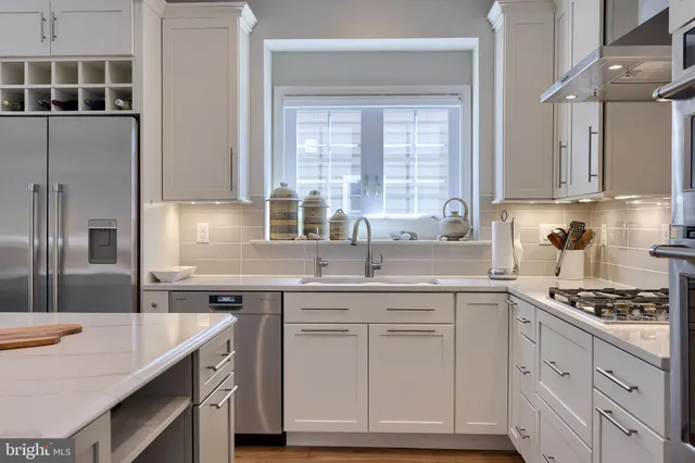 a kitchen with stainless steel appliances granite countertop a refrigerator a sink a stove a dining table and chairs