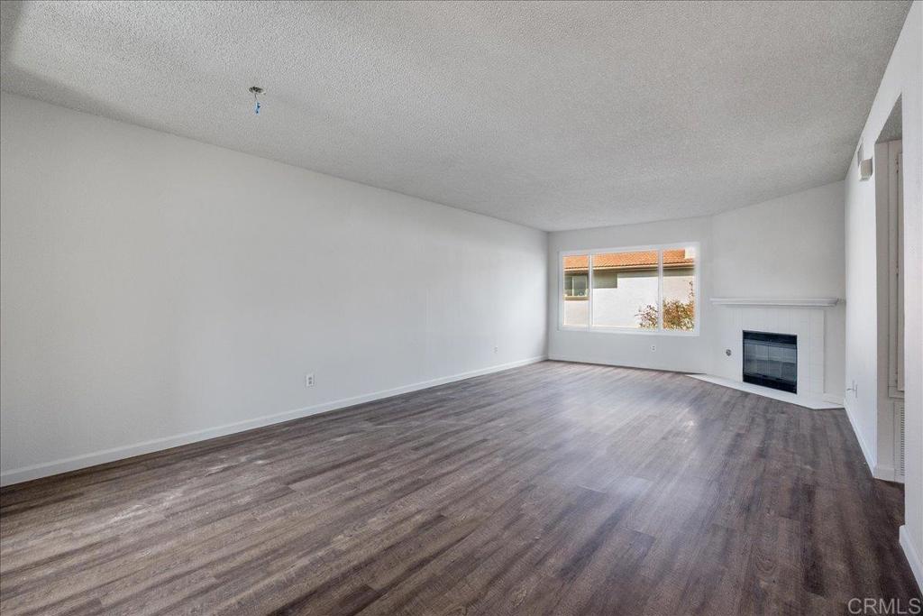 9829 Caspi Gardens Drive, Unit 6 Santee, CA 92071 - Photo 4 of 23 an empty room with wooden floor and fireplace