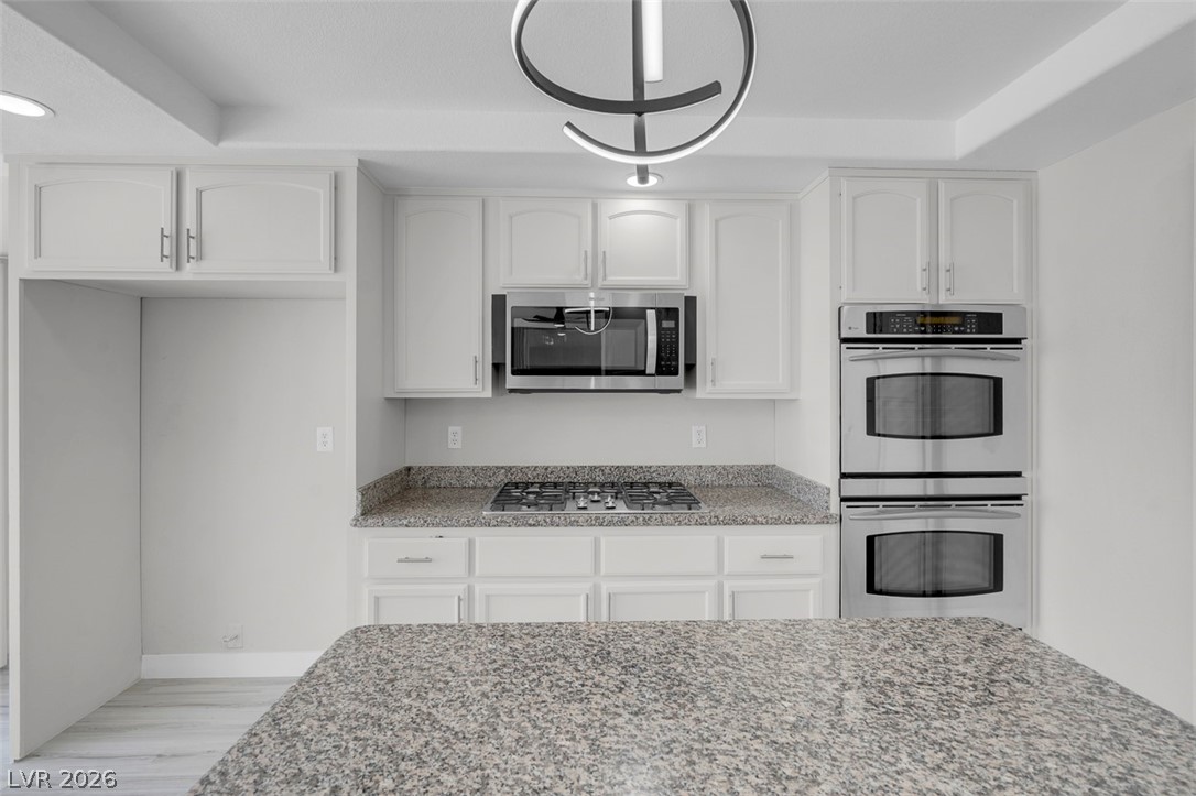 3604 North Campbell Road Las Vegas, NV 89129 - Photo 23 of 54 Kitchen with stainless steel appliances, light stone countertops, white cabinets, and light wood-type flooring