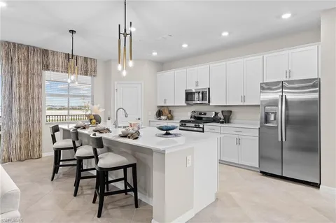 a kitchen with stainless steel appliances granite countertop a sink a stove a refrigerator cabinets and chairs