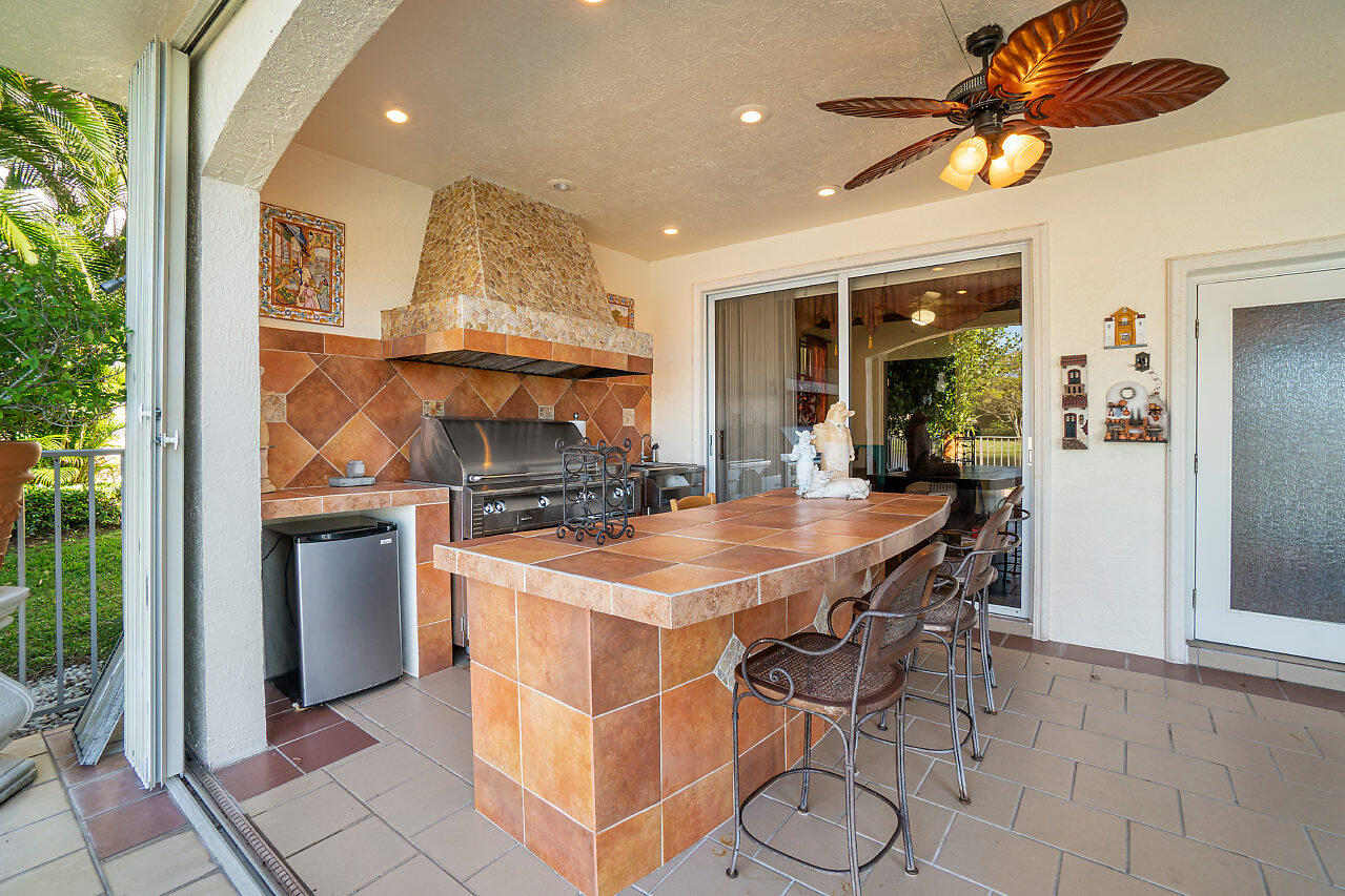 4407 Woodfield Boulevard Boca Raton, FL 33434 - Photo 33 of 37 a kitchen with stainless steel appliances kitchen island granite countertop a table chairs in it and wooden floors