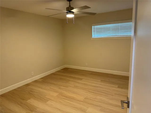 an empty room with a window and ceiling fan