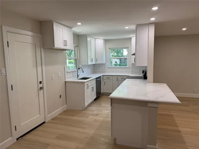 a kitchen with a sink a stove cabinets and wooden floor