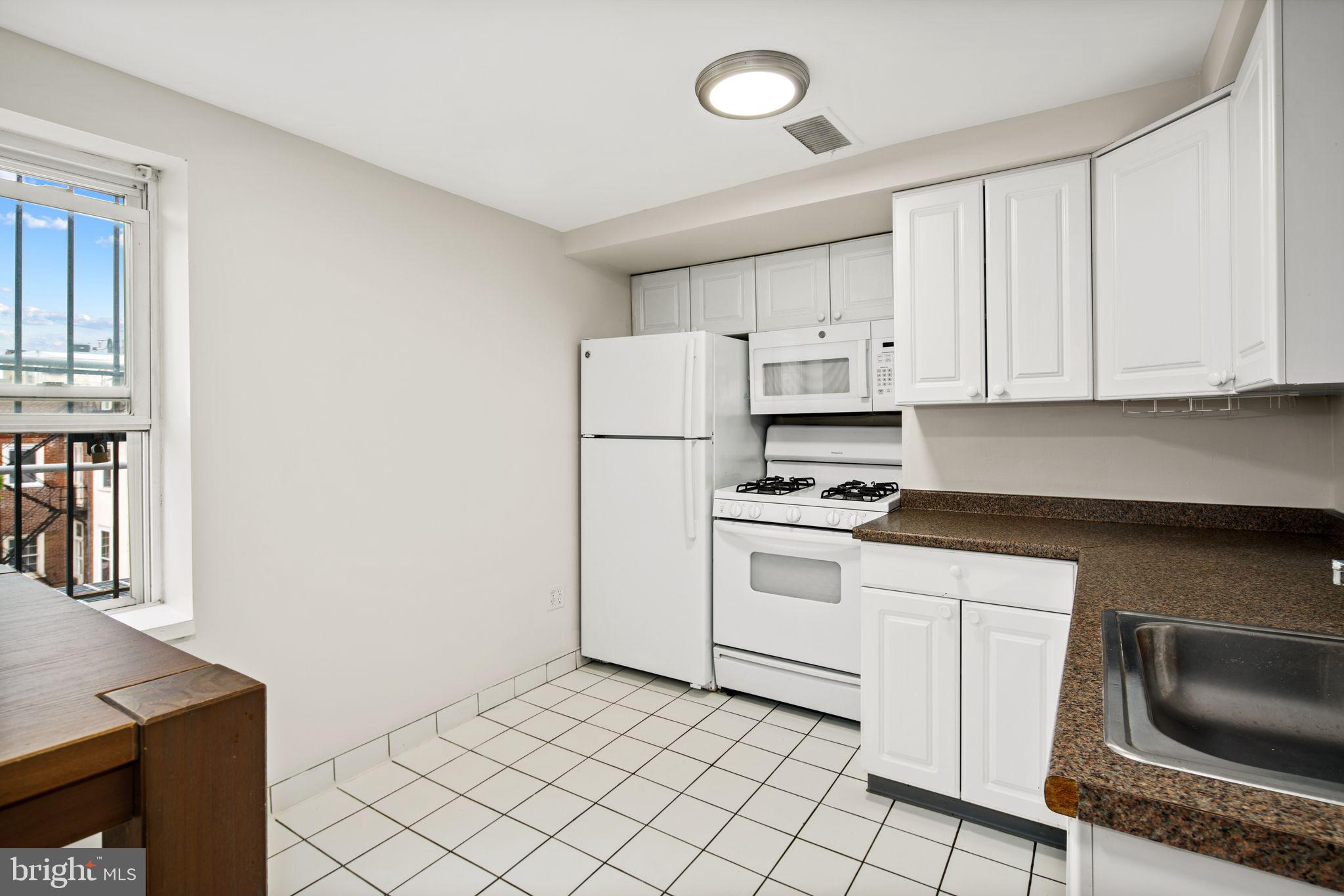 303 South 11th Street, Unit 9 Philadelphia, PA 19107 - Photo 24 of 36 a kitchen with white cabinets and white appliances