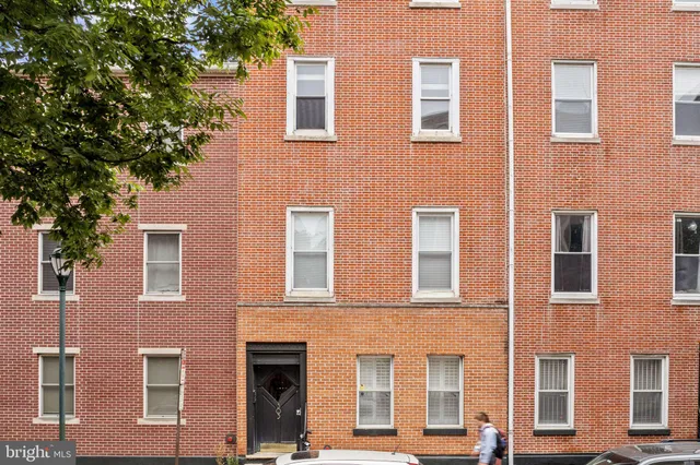 a front view of a building with a tree