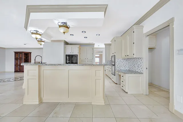 a kitchen with white cabinets and chandelier
