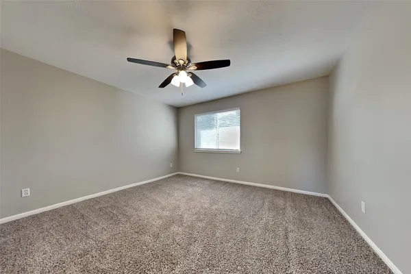 an empty room with a window and a fan
