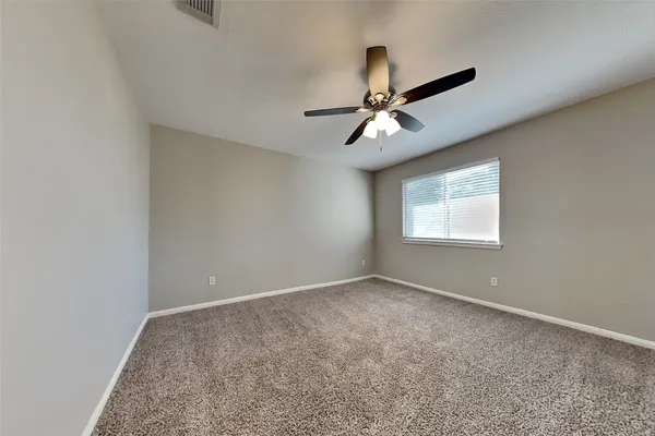 an empty room with a chandelier fan and windows