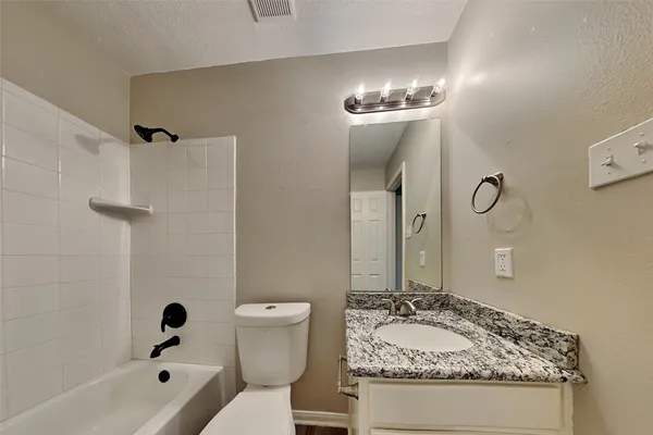 a bathroom with a granite countertop sink a toilet a mirror and shower
