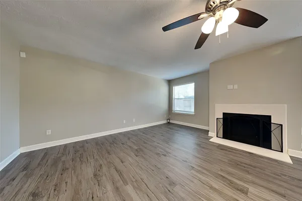 an empty room with wooden floor ceiling fan and windows